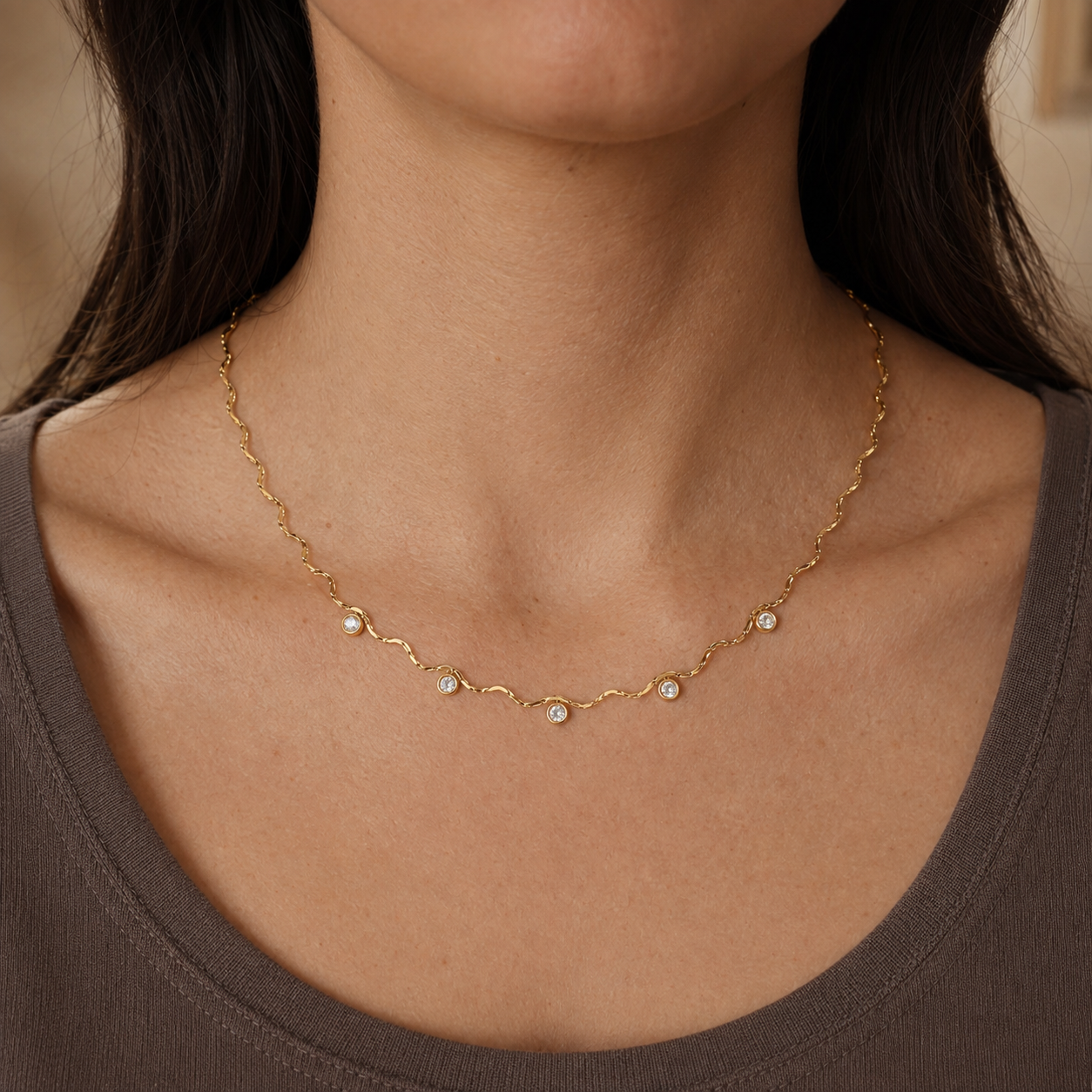 Goldene Wellenkette mit fünf Zirkonia am Hals getragen