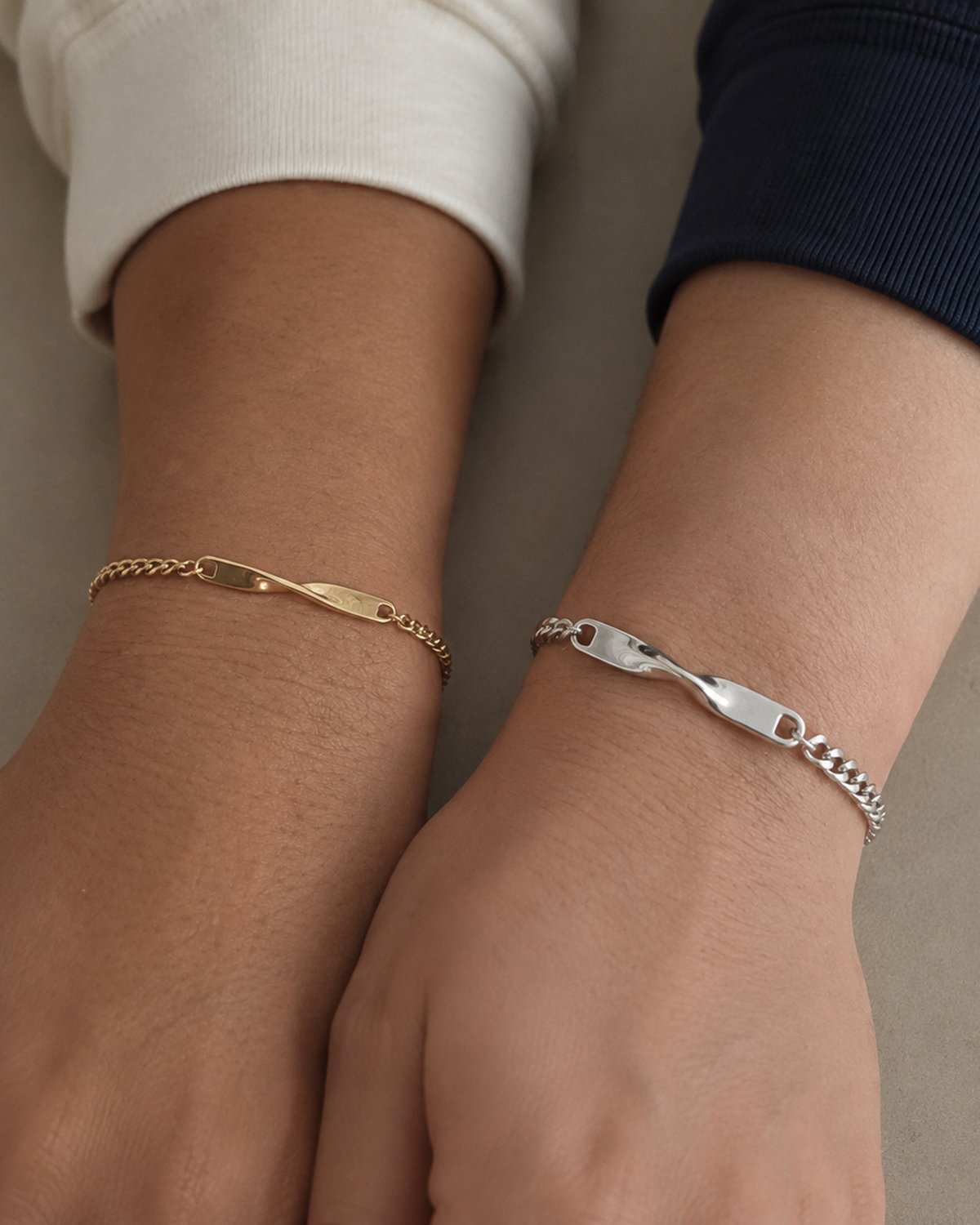 Zwei Twist Armbänder in Gold und Silber an nebeneinanderliegenden Handgelenken all-groups