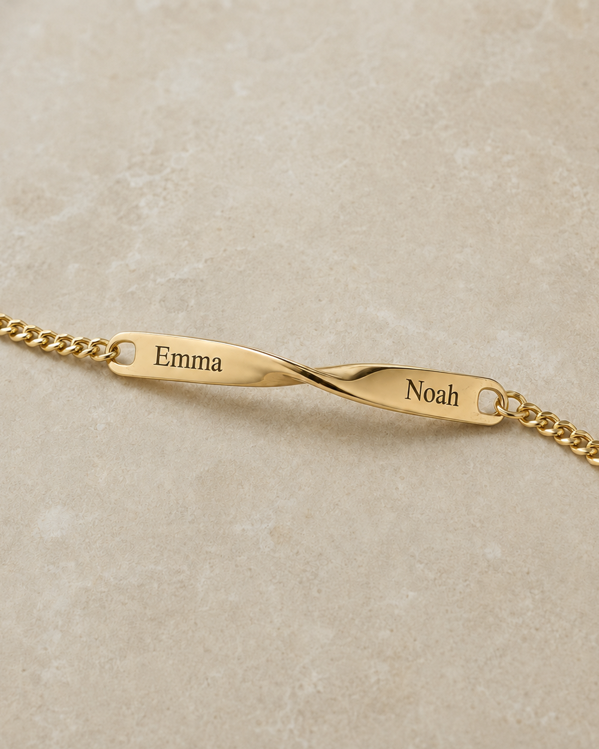 Goldenes Twist Armband mit Beispielgravur Emma links und Noah rechts neben der Verdrehung all-groups
