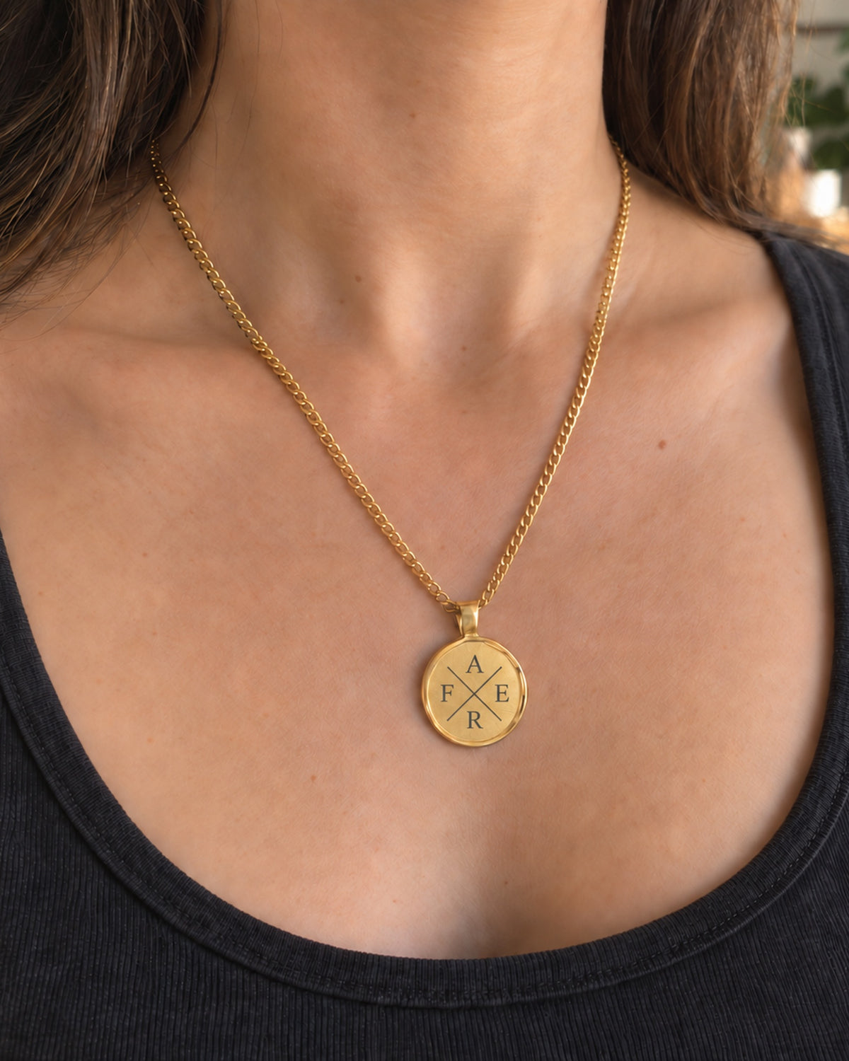 Goldfarbene Relic Coin Halskette an einer Frau mit dunklem Oberteil; digitales Initialenkreuz. all-groups