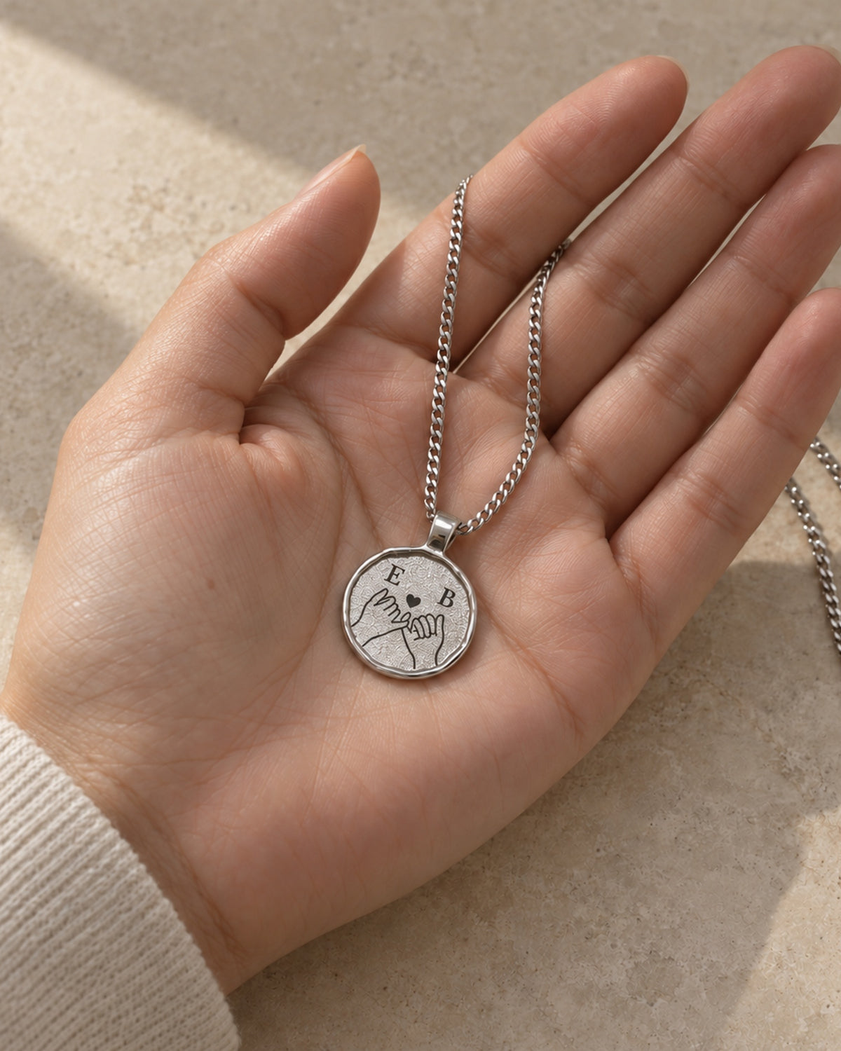 Silberfarbene Relic Coin Halskette in einer Hand mit digitalem Fingerschwurmotiv. all-groups