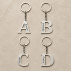 Vier silberfarbene Initial-Schlüsselanhänger A, B, C und D mit unterschiedlichen Namensgravuren.  | all-groups