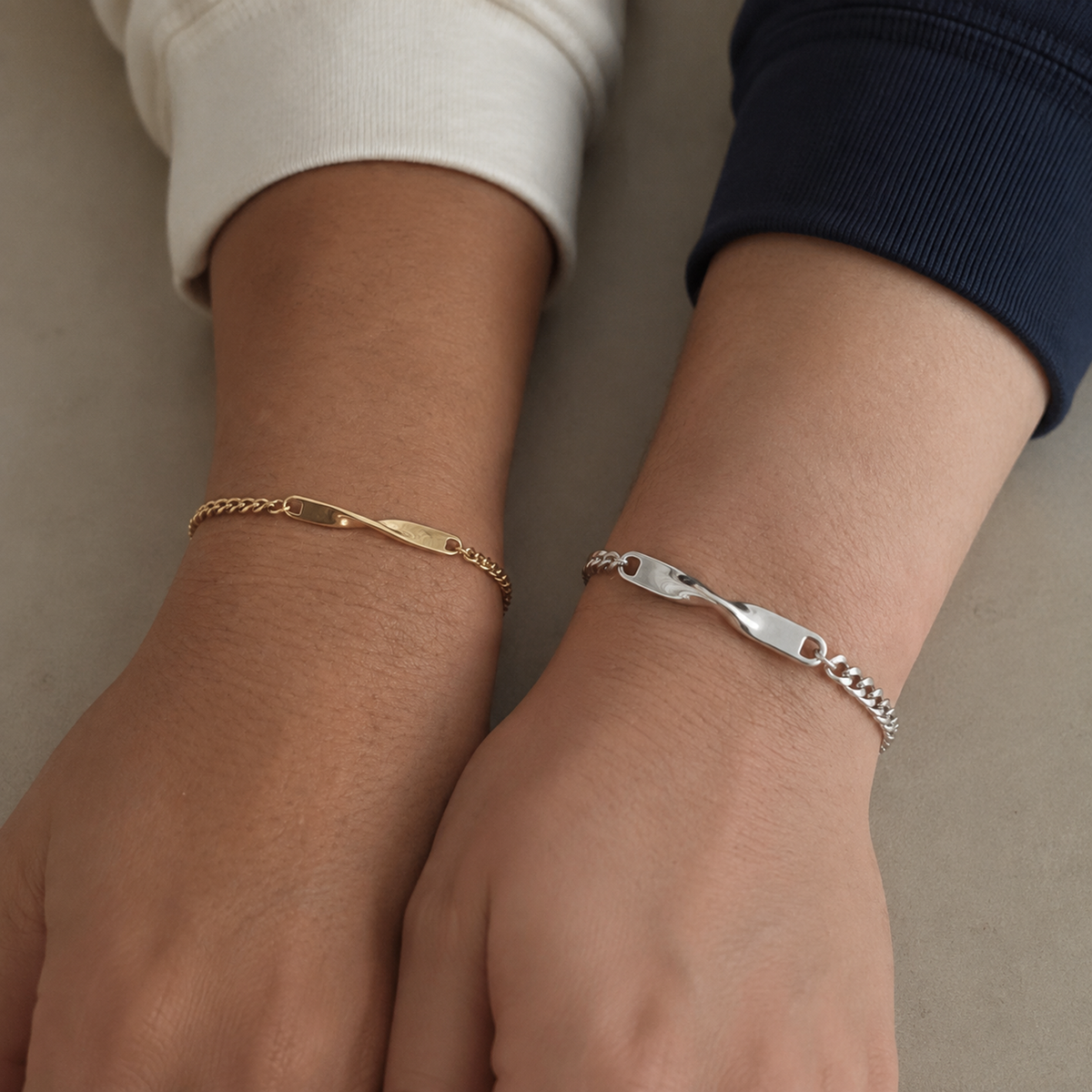 Zwei Twist Armbänder in Gold und Silber an nebeneinanderliegenden Handgelenken all-groups