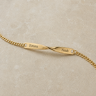 Goldenes Twist Armband mit Beispielgravur Emma links und Noah rechts neben der Verdrehung all-groups