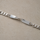 Nahaufnahme des silbernen Twist Plättchens mit mittiger Verdrehung und Kettenanschlüssen all-groups
