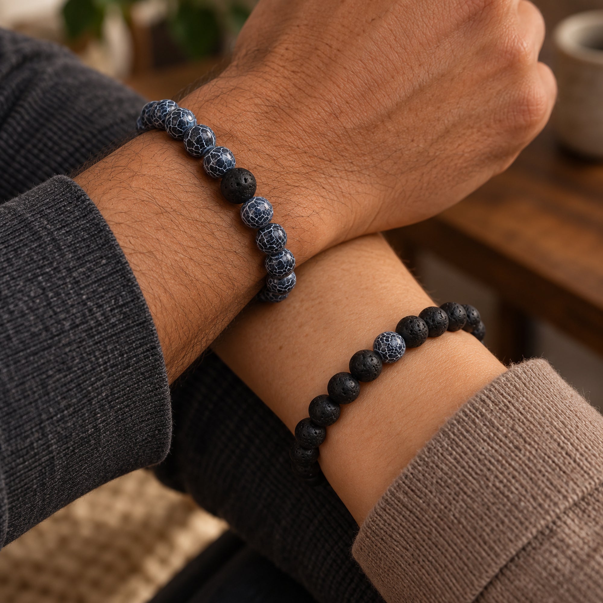 Zwei gekreuzte Handgelenke mit blauen und schwarzen Perlenarmbändern