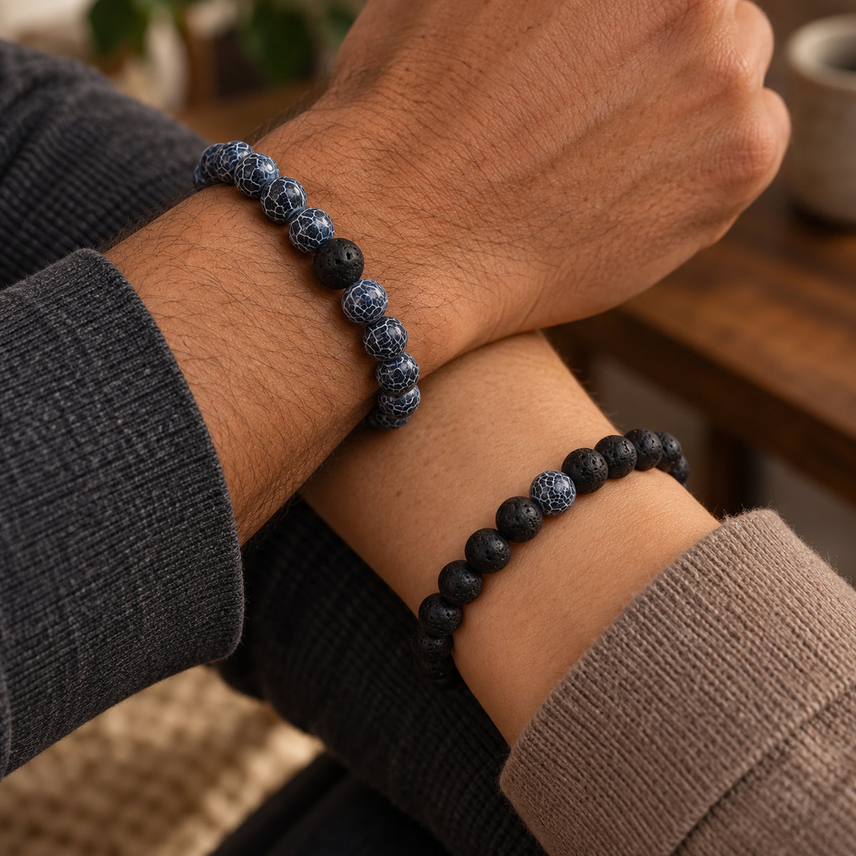 Zwei gekreuzte Handgelenke mit blauen und schwarzen Perlenarmbändern