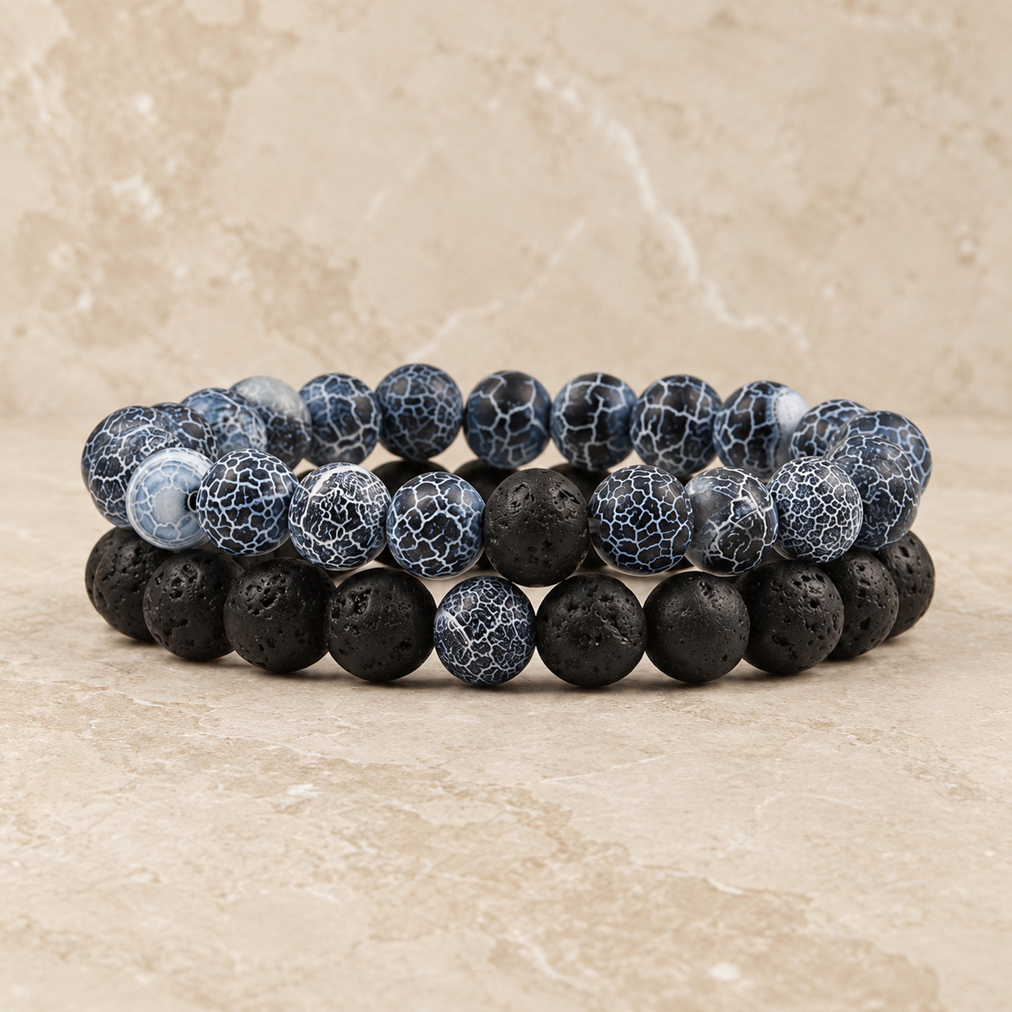 Zwei Perlenarmbänder in Blau und Schwarz auf hellem Stein