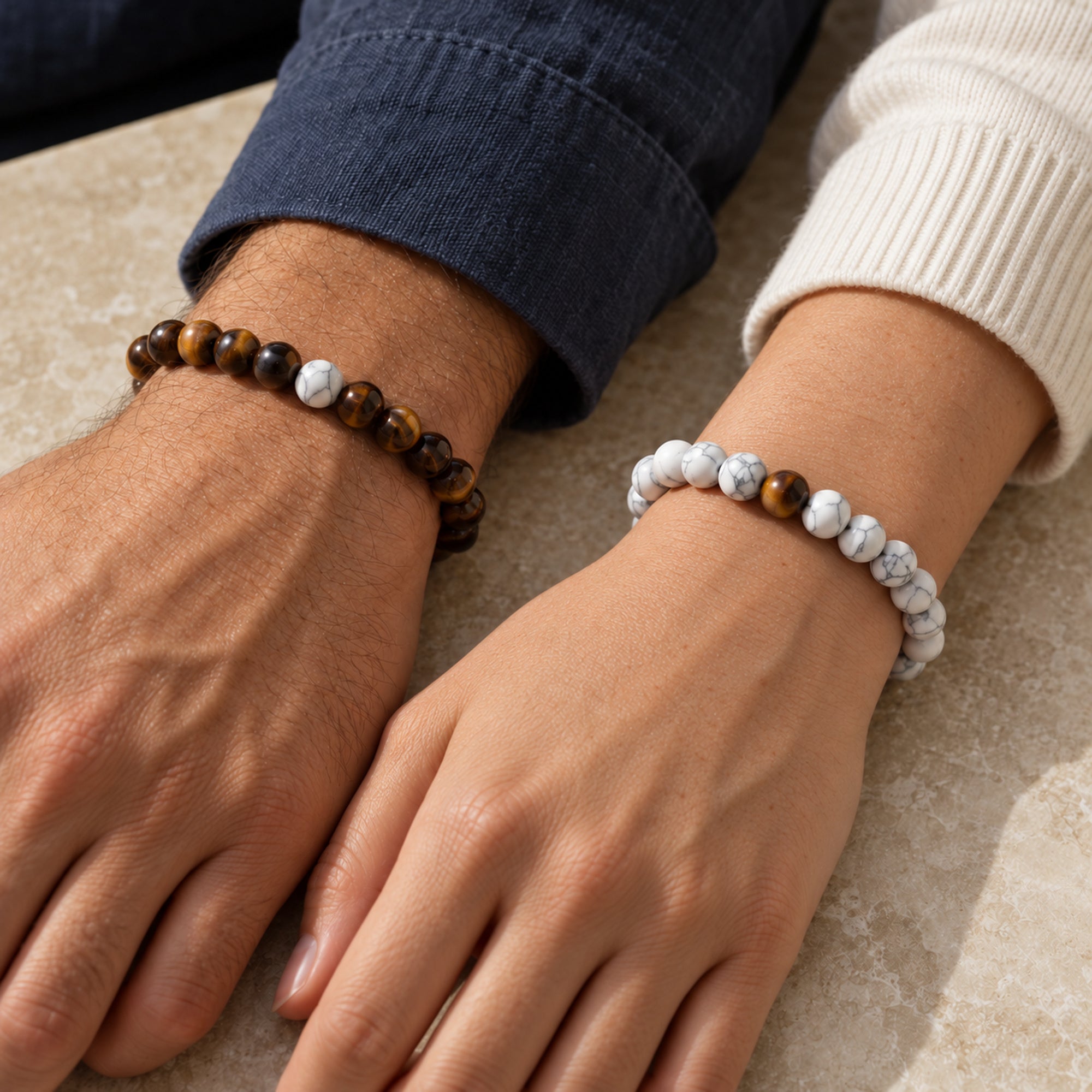 Zwei Menschen tragen die weißen und braunen Perlenarmbänder