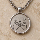 Silberfarbener Relic Coin Anhänger mit digitalem Fingerschwurmotiv und zwei Initialen. all-groups