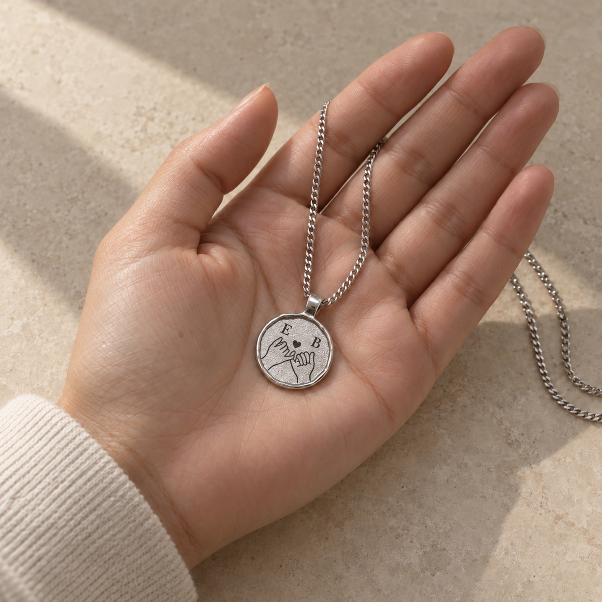 Silberfarbene Relic Coin Halskette in einer Hand mit digitalem Fingerschwurmotiv. all-groups