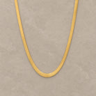 Sleek Chain in Gold auf warmem mineralischem Untergrund