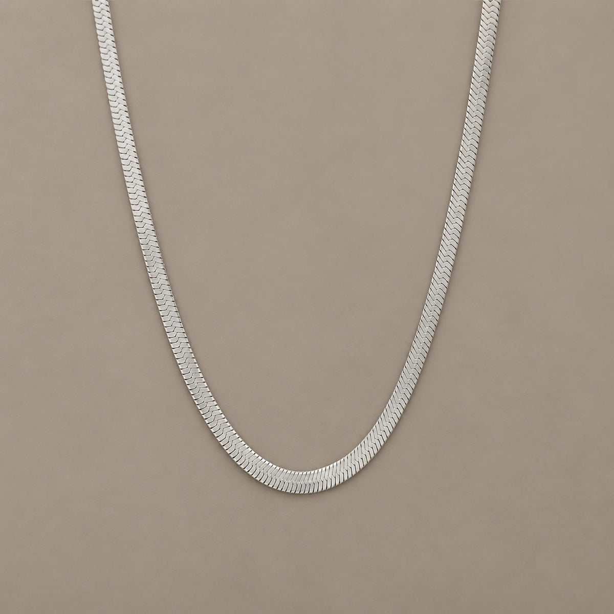 Sleek Chain in Silber auf warmem mineralischem Untergrund